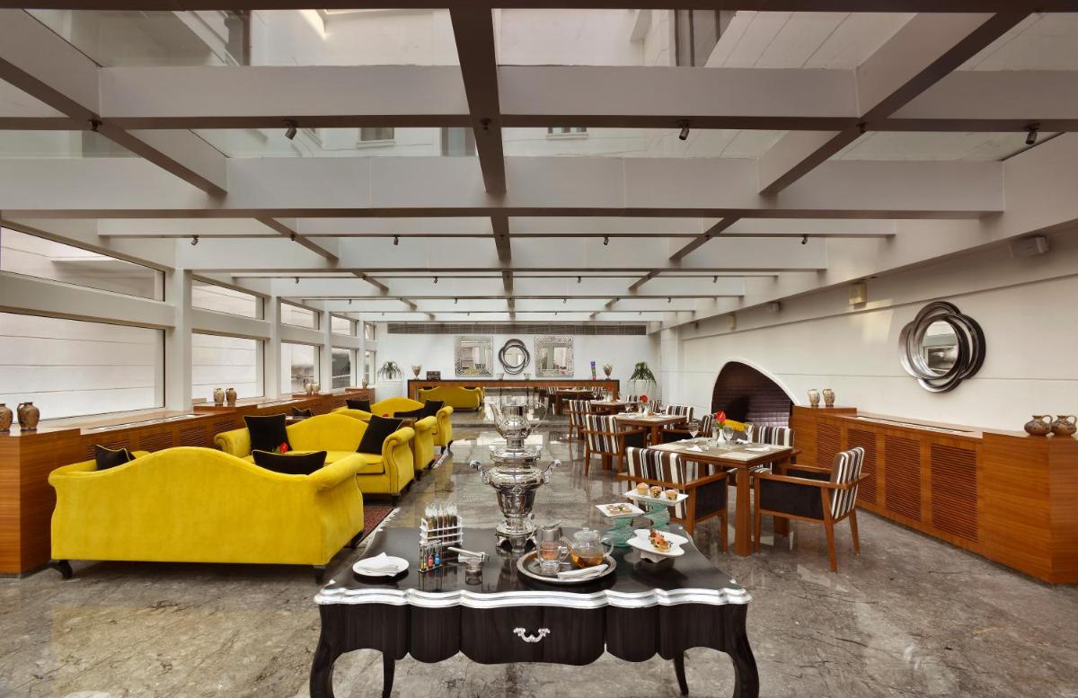 a dining room with tables and yellow chairs at The Lalit Great Eastern Kolkata in Kolkata a dining room with tables and yellow chairs at The Lalit Great Eastern Kolkata in Kolkata