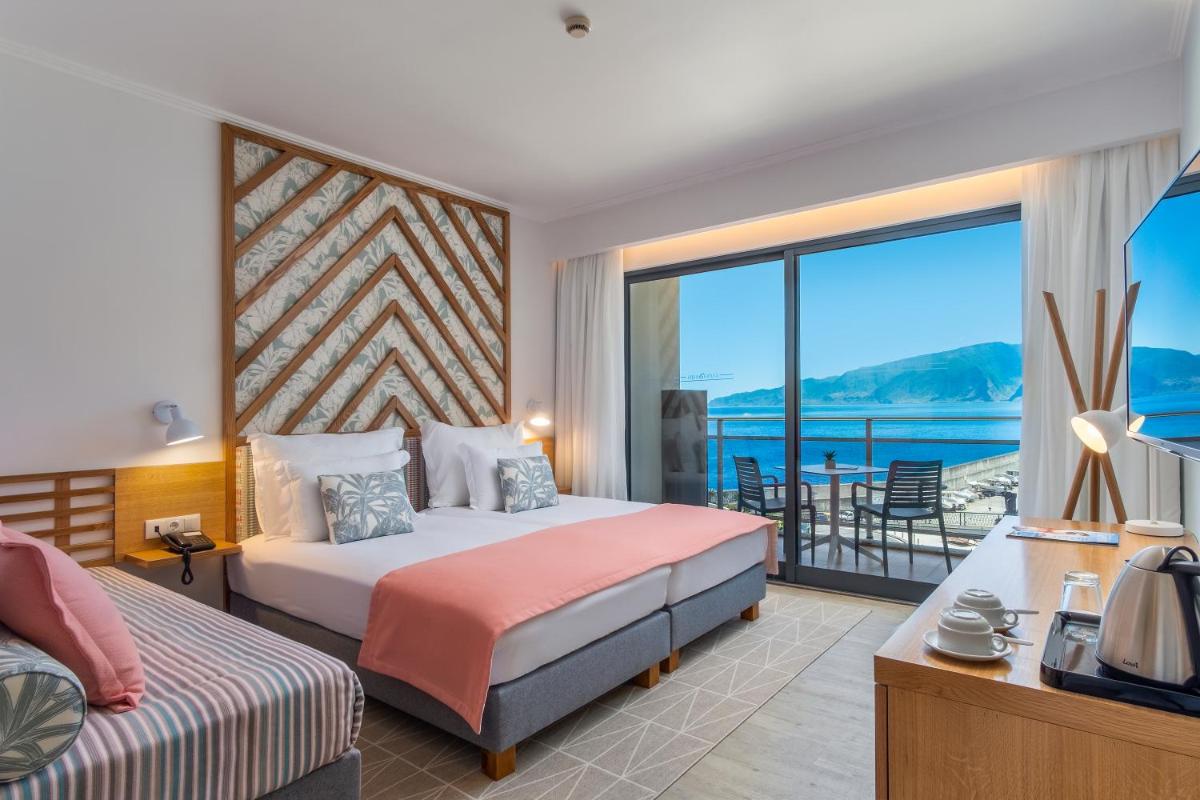um quarto de hotel com duas camas e uma varanda em Aqua Natura Bay em Porto Moniz um quarto de hotel com duas camas e uma varanda em Aqua Natura Bay em Porto Moniz