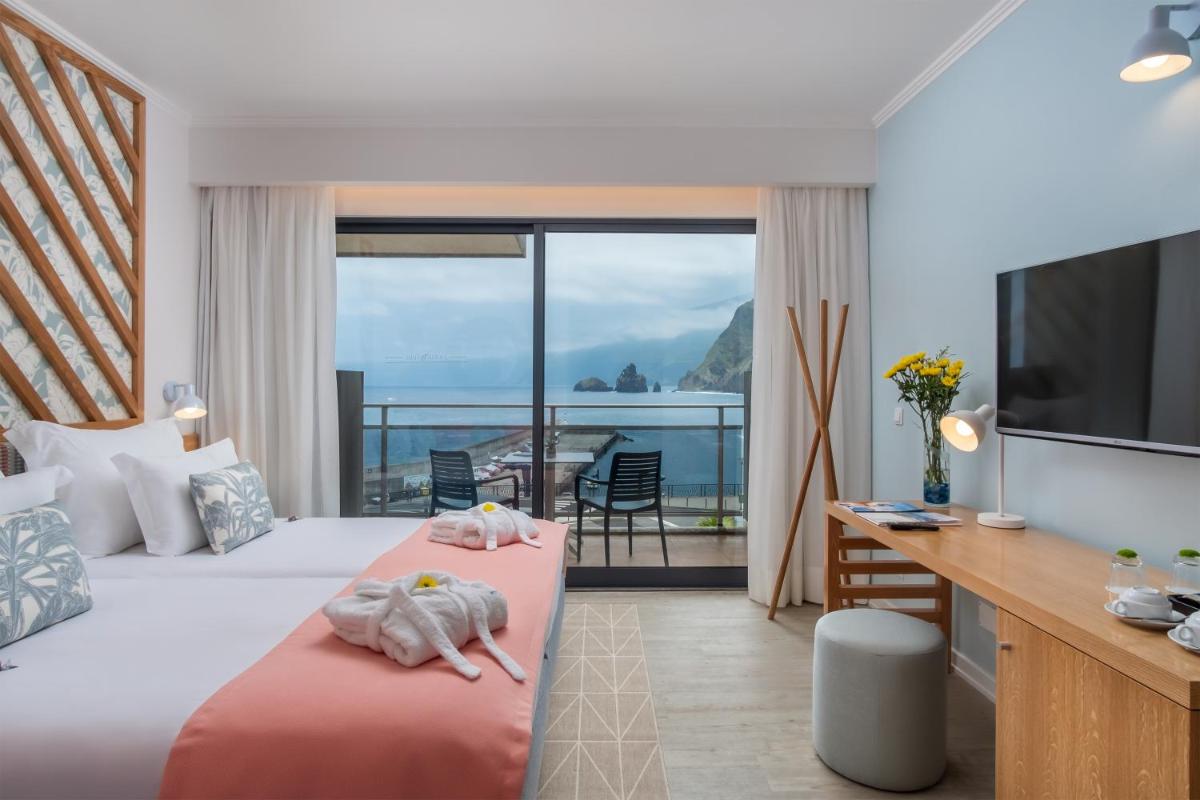 um quarto de hotel com duas camas e uma varanda em Aqua Natura Bay em Porto Moniz um quarto de hotel com duas camas e uma varanda em Aqua Natura Bay em Porto Moniz