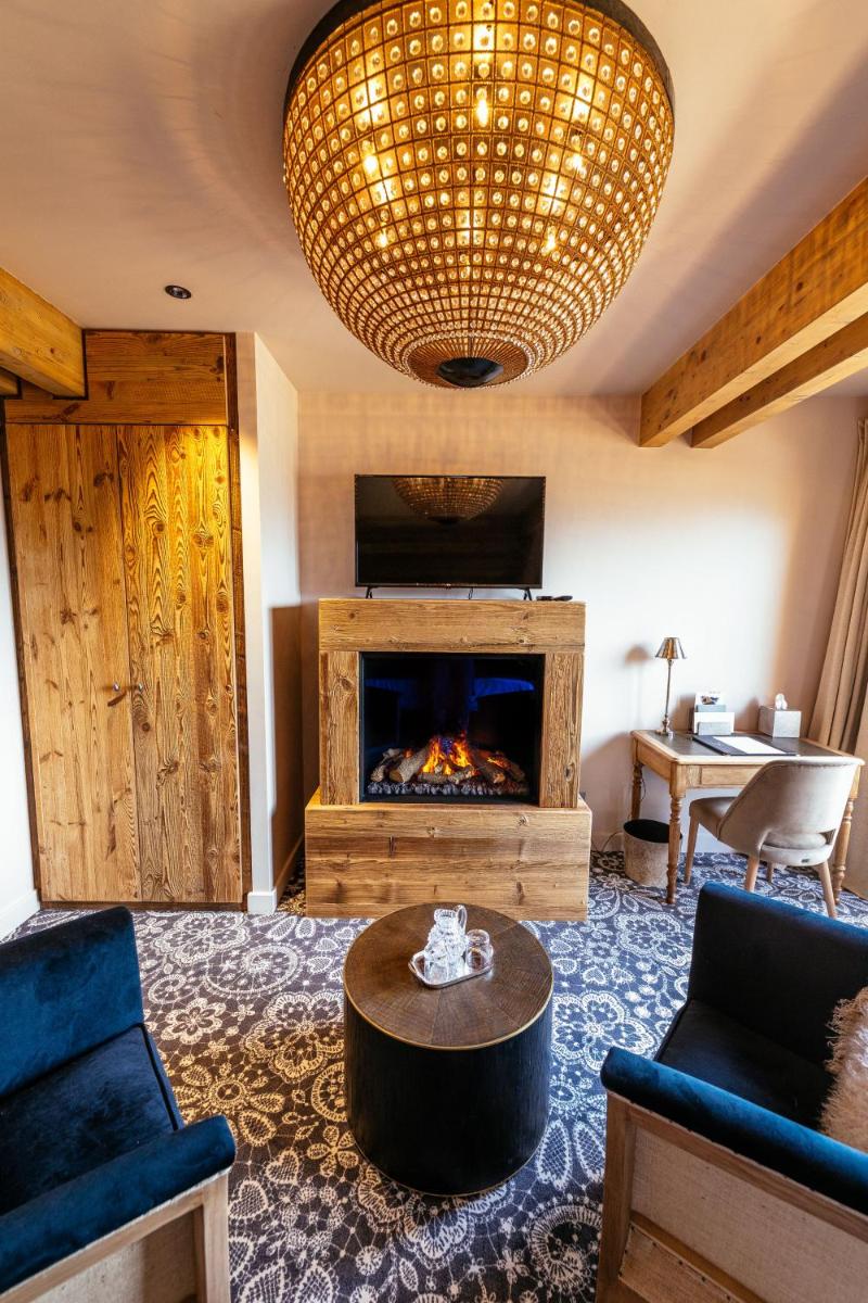 d'un salon avec une cheminée et un lustre. dans l'établissement Hotel Le V de Vaujany, à Vaujany