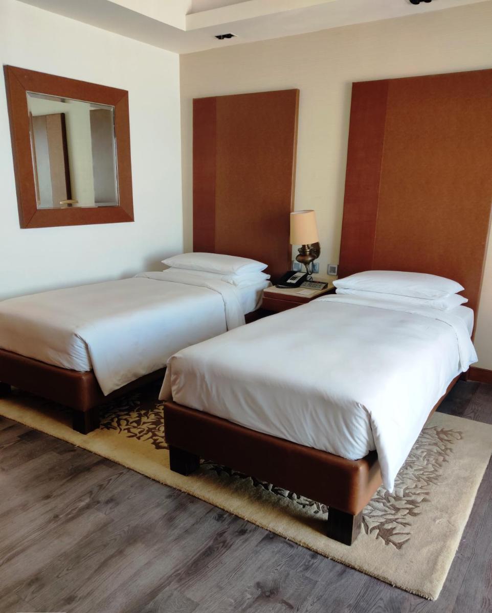 two beds in a hotel room with a mirror at Hyatt Ahmedabad in Ahmedabad