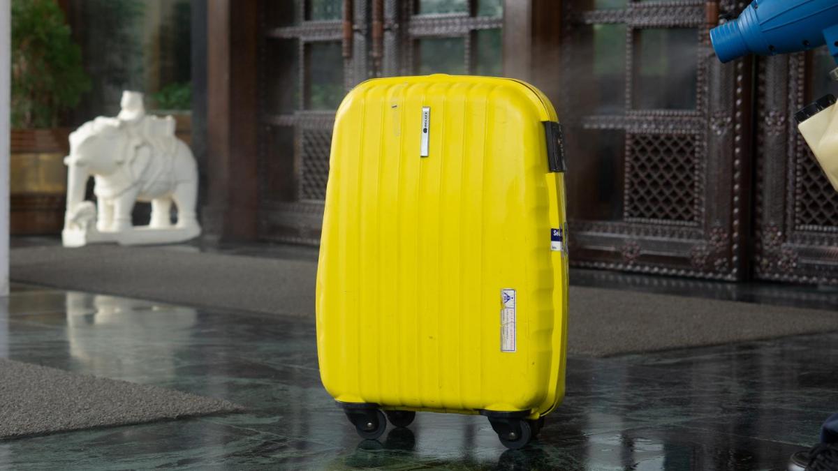 a yellow suitcase is standing in the rain at The Ummed Ahmedabad Airport in Ahmedabad