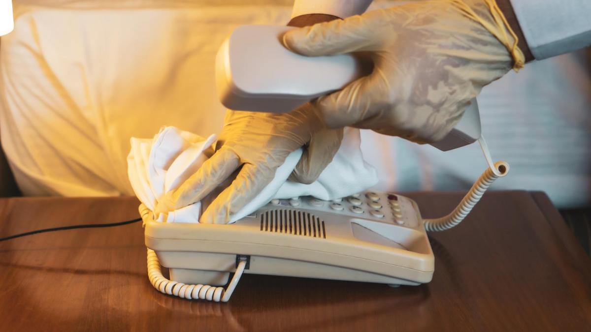a person in gloves holding a phone on a table at The Ummed Ahmedabad Airport in Ahmedabad