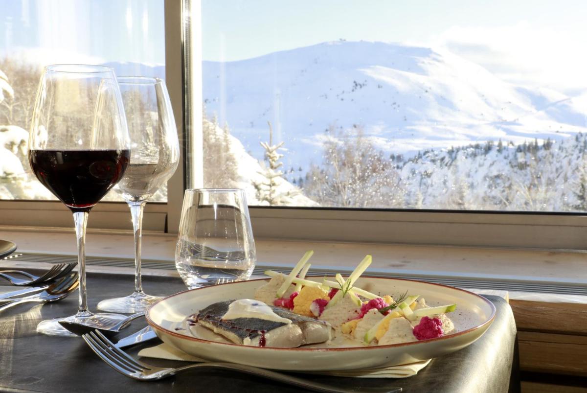 une assiette de nourriture sur une table avec des verres à vin dans l'établissement Le Pic Blanc, à L'Alpe-d'Huez