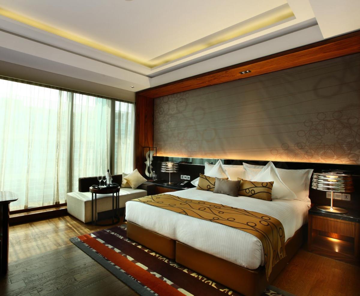a bedroom with a large bed and a living room at Crowne Plaza New Delhi Rohini by IHG in New Delhi a bedroom with a large bed and a living room at Crowne Plaza New Delhi Rohini by IHG in New Delhi