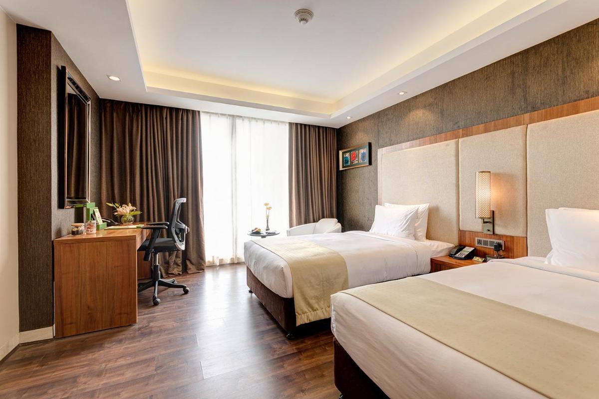 a hotel room with two beds and a desk at Holiday Inn Kolkata Airport by IHG in Kolkata
