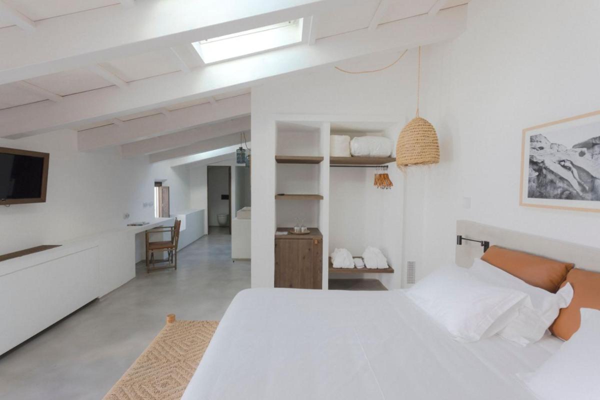 Un dormitorio blanco con una cama grande y un televisor. en Can Araya, en Ciutadella