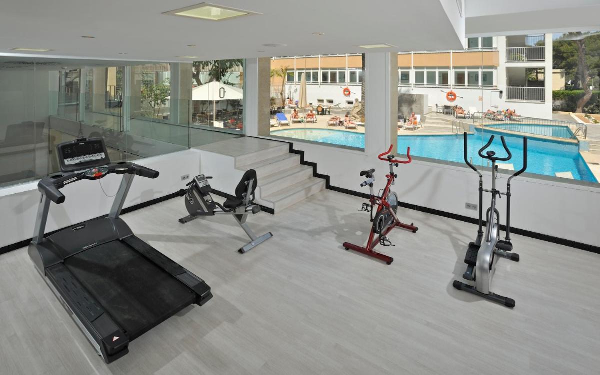 un gimnasio con 3 bicicletas estáticas y una piscina en Hotel Hispania, en Playa de Palma