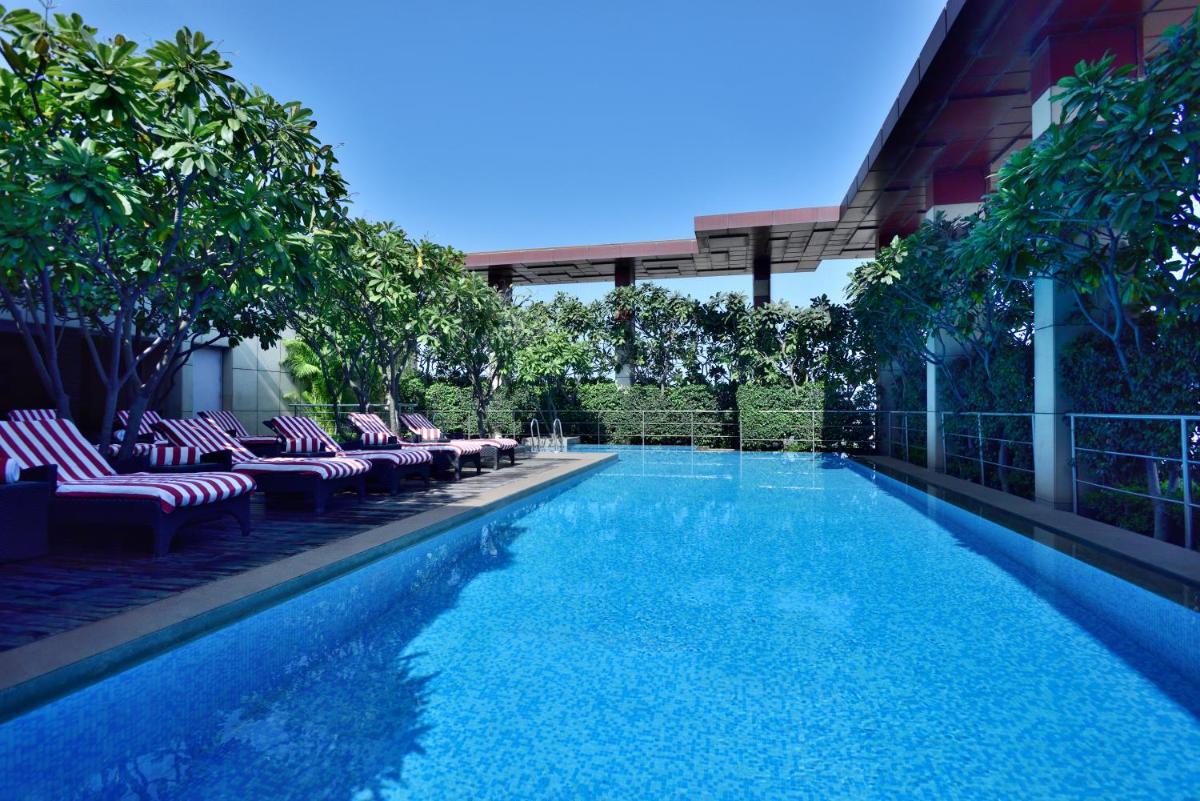 a large swimming pool with lounge chairs and trees at Radisson Blu Hotel, Indore in Indore