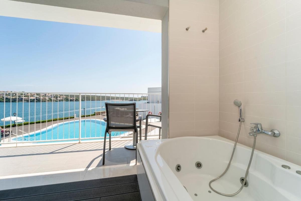 Una bañera en un baño con vistas a una piscina. en ARTIEM Carlos - Adults Only, en Es Castell