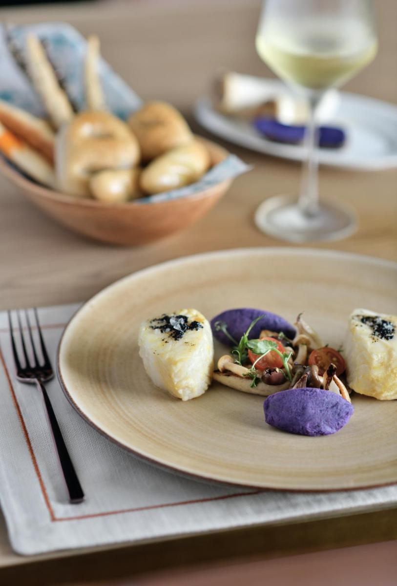 a plate of food on a table with a glass of wine at Taj Mahal, New Delhi in New Delhi