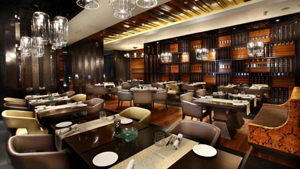 a restaurant with tables and chairs and books at Crowne Plaza New Delhi Rohini by IHG in New Delhi a restaurant with tables and chairs and books at Crowne Plaza New Delhi Rohini by IHG in New Delhi