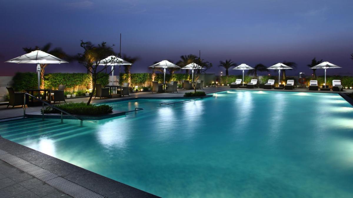 a pool at night with umbrellas and chairs at Crowne Plaza New Delhi Rohini by IHG in New Delhi a pool at night with umbrellas and chairs at Crowne Plaza New Delhi Rohini by IHG in New Delhi