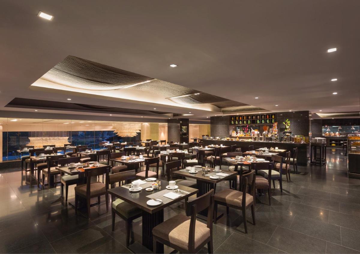 a restaurant with tables and chairs and a bar at Crowne Plaza Kochi by IHG in Cochin
