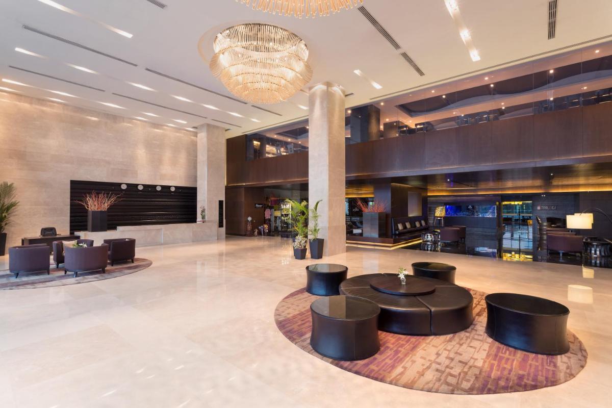 a lobby with tables and chairs in a building at Crowne Plaza Kochi by IHG in Cochin