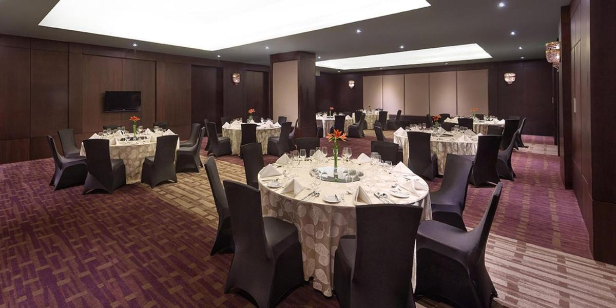 a banquet room with tables and chairs and a television at Crowne Plaza Kochi by IHG in Cochin