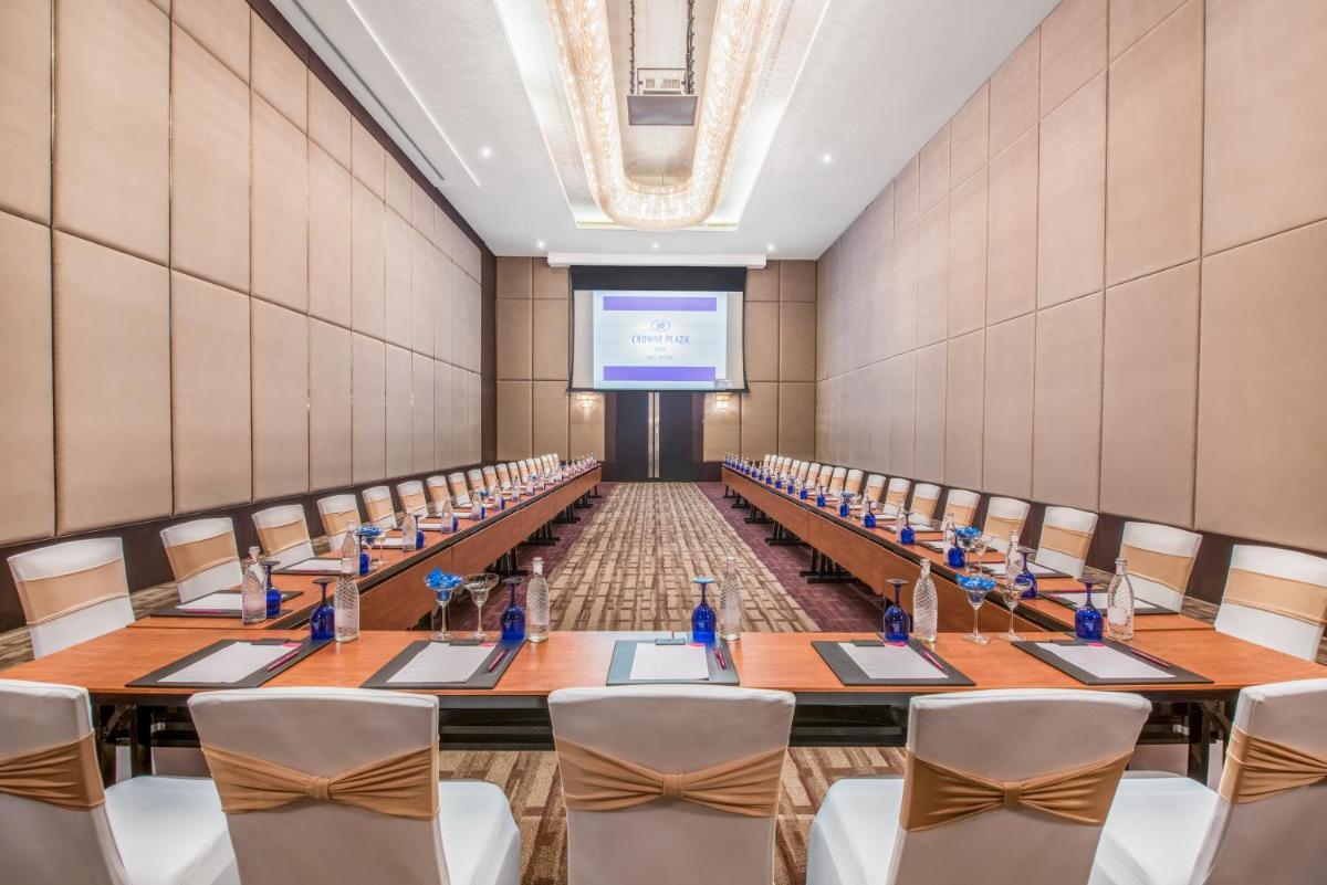 a large room with tables and chairs and a projection screen at Crowne Plaza Kochi by IHG in Cochin