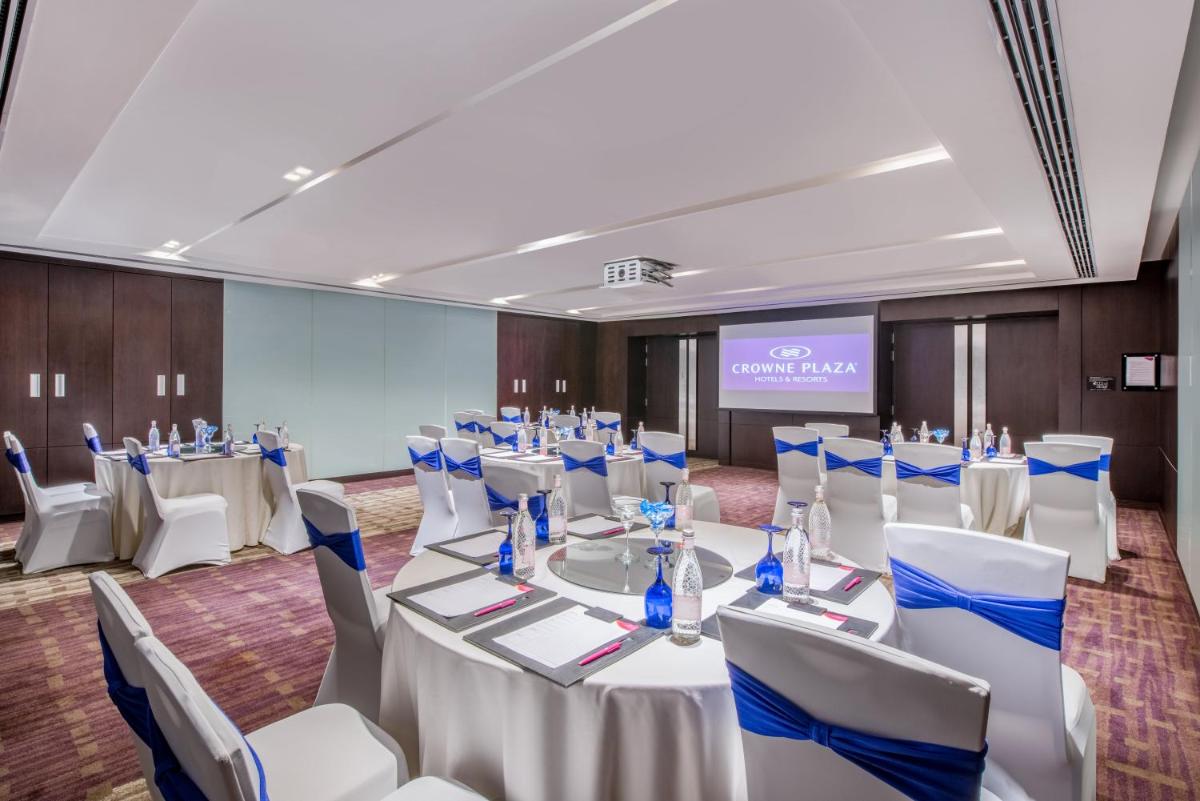a conference room with white tables and chairs and a screen at Crowne Plaza Kochi by IHG in Cochin