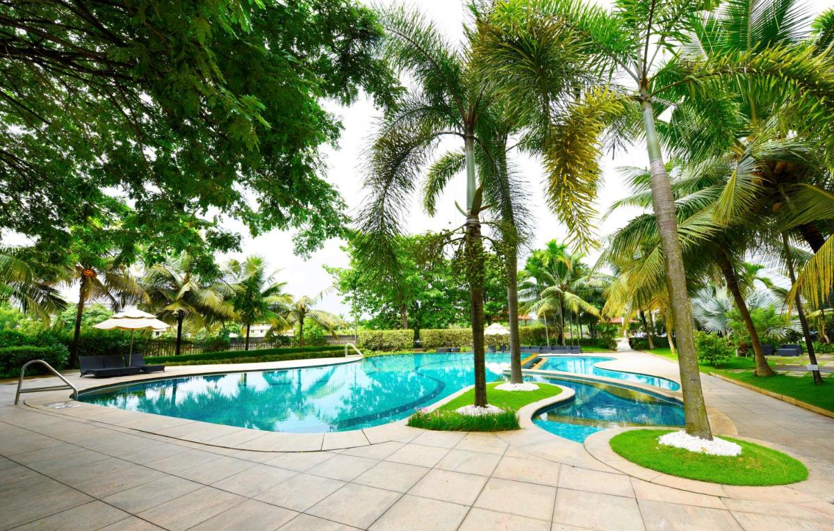 a swimming pool with palm trees in a resort at Crowne Plaza Kochi by IHG in Cochin