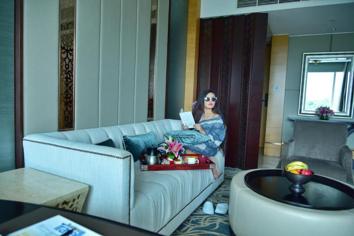 a woman sitting on a couch reading a book at Shangri-La Bengaluru in Bengaluru a woman sitting on a couch reading a book at Shangri-La Bengaluru in Bengaluru