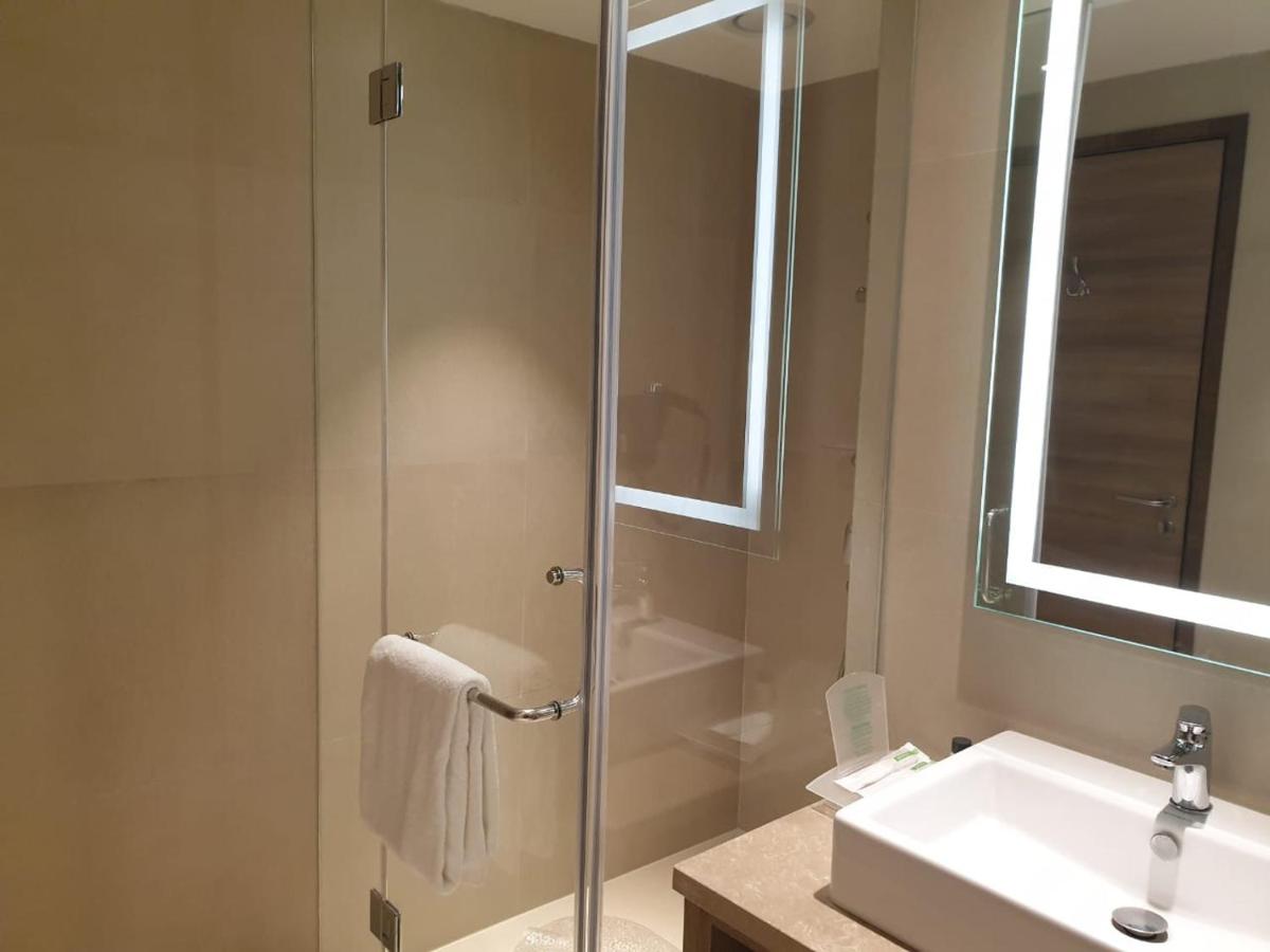 a bathroom with a shower and a sink and a mirror at Holiday Inn Gurugram Sector 90 by IHG in Gurgaon