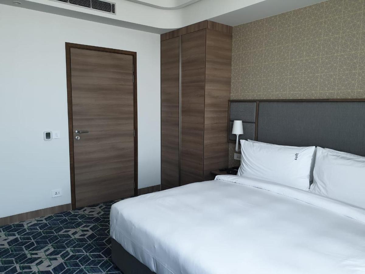 a bedroom with a large bed and a wooden door at Holiday Inn Gurugram Sector 90 by IHG in Gurgaon