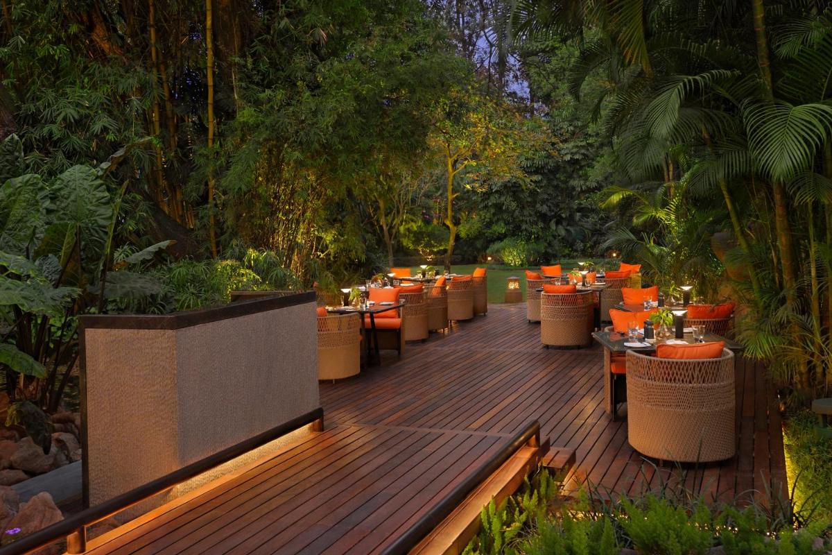 a restaurant with tables and chairs on a wooden deck at The Oberoi Bengaluru in Bengaluru a restaurant with tables and chairs on a wooden deck at The Oberoi Bengaluru in Bengaluru