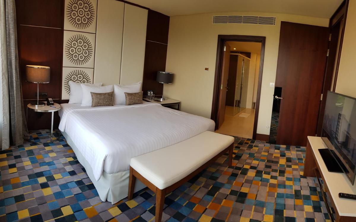 a hotel room with a bed and a television at Novotel Kochi Infopark in Cochin