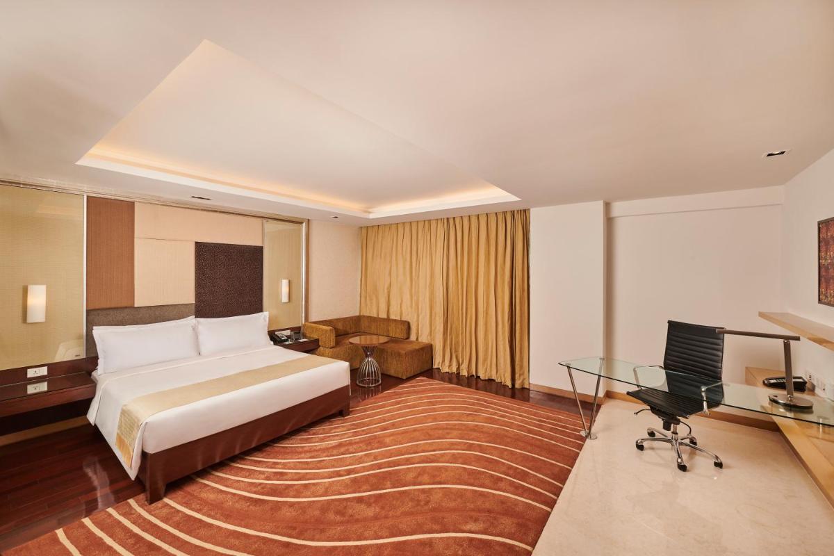 a hotel room with a bed and a desk at Holiday Inn Mumbai International Airport by IHG in Mumbai