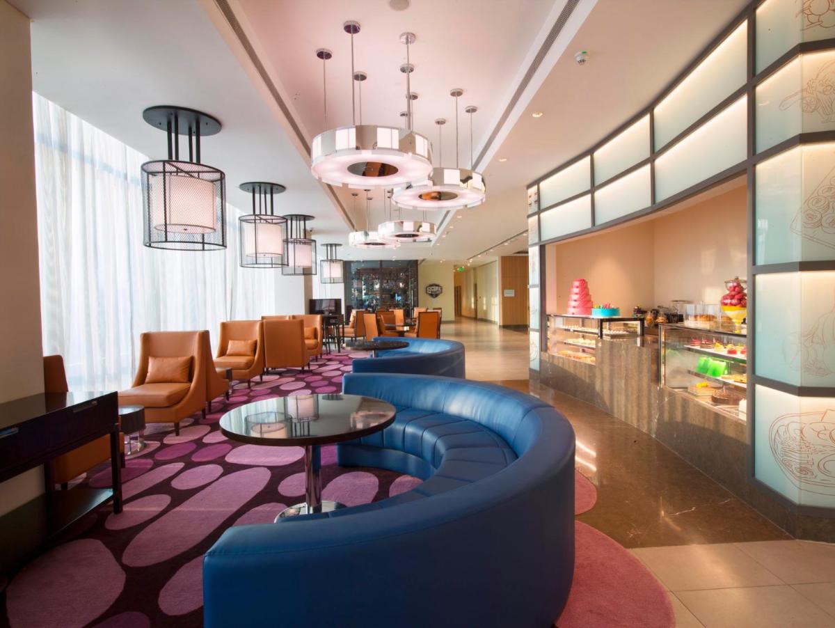 a lobby of a hotel with blue chairs and tables at Holiday Inn Chennai OMR IT Expressway by IHG in Chennai