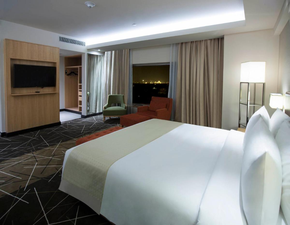 a hotel room with a large white bed and a television at Holiday Inn Chennai OMR IT Expressway by IHG in Chennai