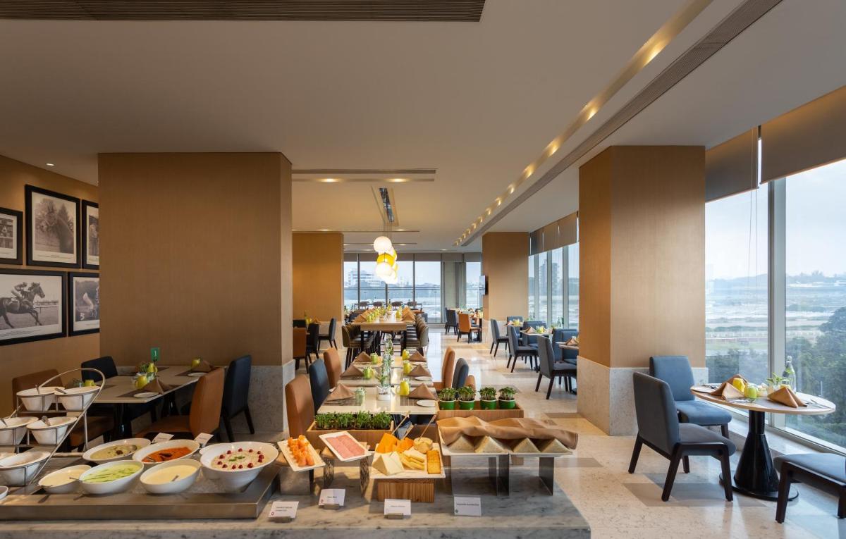 a restaurant with a buffet of food and tables at Holiday Inn Bengaluru Racecourse by IHG in Bengaluru a restaurant with a buffet of food and tables at Holiday Inn Bengaluru Racecourse by IHG in Bengaluru