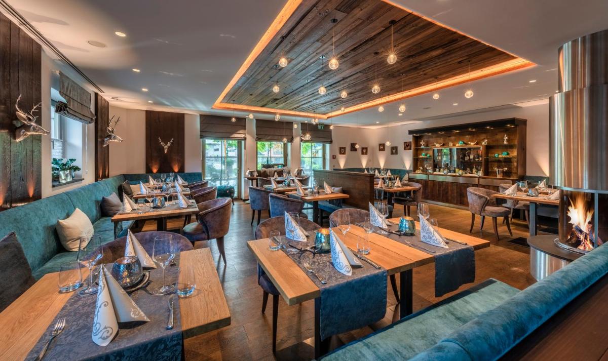 ein Restaurant mit Holztischen und blauen Sofas in der Unterkunft Hotel Maximilian in Oberammergau