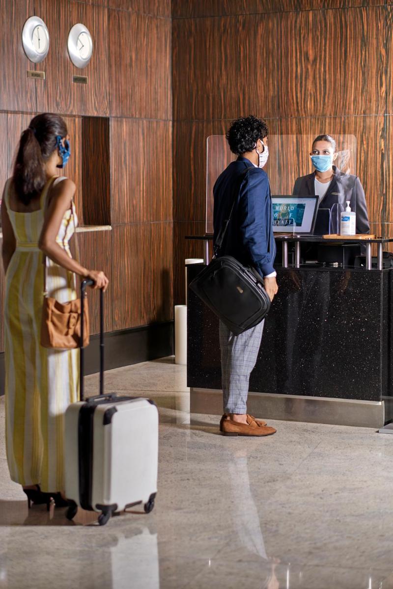 a man with a suitcase and a woman wearing a mask at Hyatt Regency Chandigarh in Chandīgarh