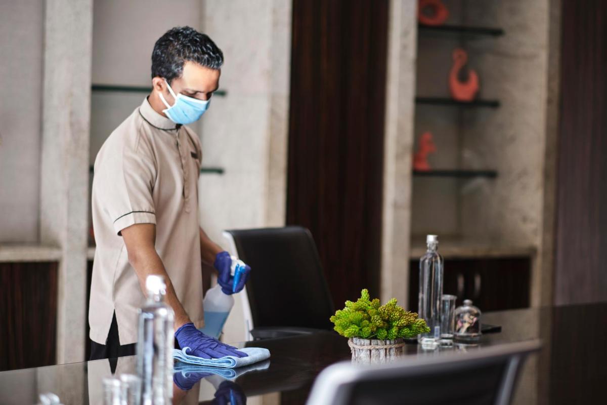 a man in a mask is cleaning a table at Hyatt Regency Chandigarh in Chandīgarh