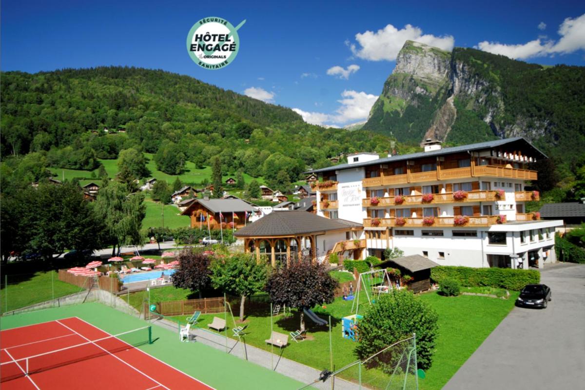 un hôtel avec un court de tennis face à une montagne dans l'établissement Chalet-Hôtel Neige et Roc, The Originals Relais, à Samoëns
