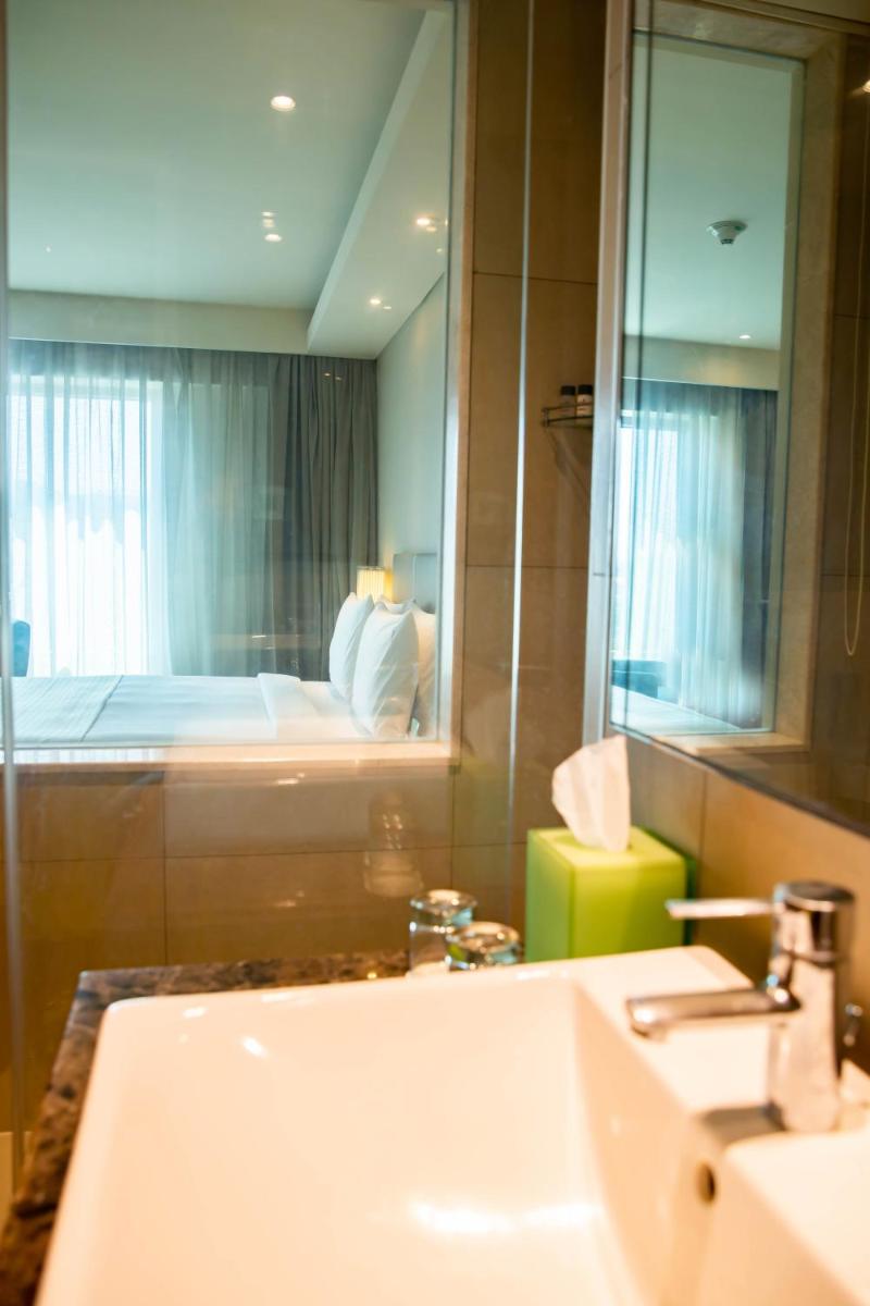a bathroom with a sink and a mirror and a bed at Holiday Inn Chennai OMR IT Expressway by IHG in Chennai