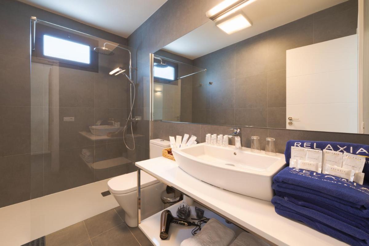 Un baño con lavabo, inodoro y espejo. en Relaxia Lanzasur Club - Aqualava Water Park, en Playa Blanca
