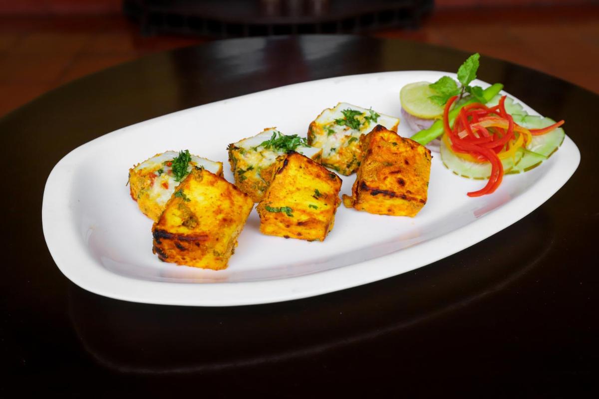a plate of food with tofu and salad on a table at The Grand Imperial - Heritage Hotel in Agra