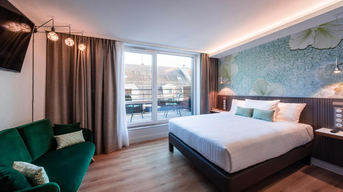 une chambre avec un lit, un canapé et une fenêtre dans l'établissement voco Strasbourg Centre - The Garden by IHG, à Strasbourg