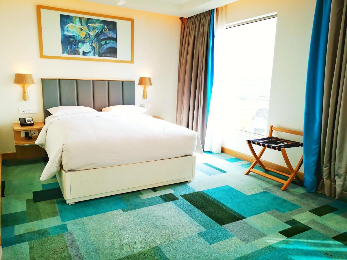 a bedroom with a bed and a large window at Holiday Inn Bengaluru Racecourse by IHG in Bengaluru a bedroom with a bed and a large window at Holiday Inn Bengaluru Racecourse by IHG in Bengaluru