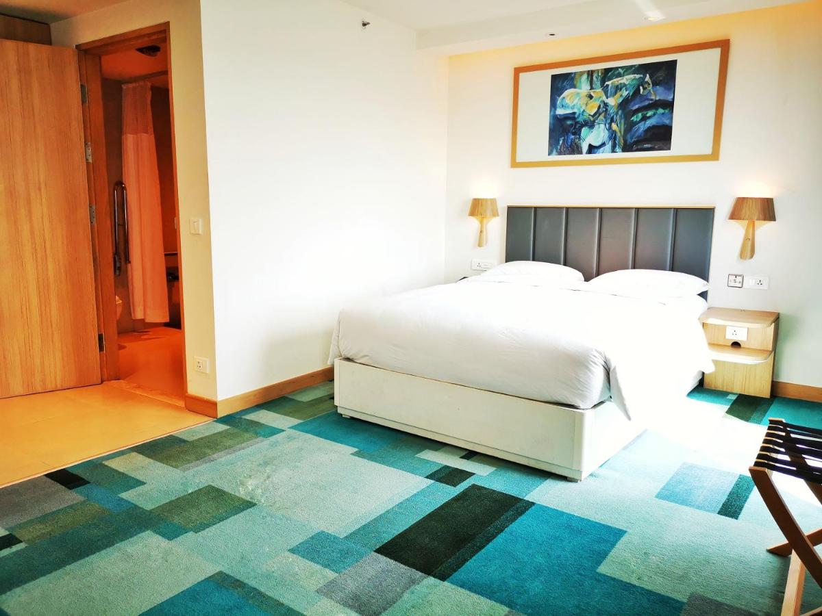 a bedroom with a white bed and a blue carpet at Holiday Inn Bengaluru Racecourse by IHG in Bengaluru a bedroom with a white bed and a blue carpet at Holiday Inn Bengaluru Racecourse by IHG in Bengaluru