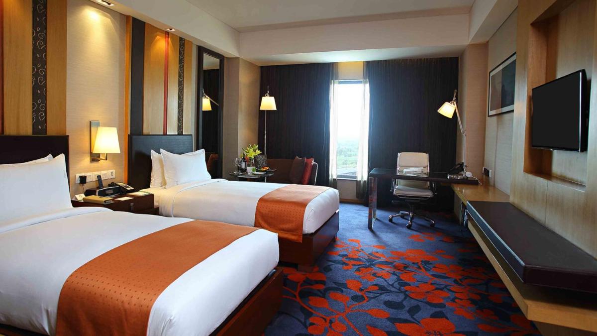 a hotel room with two beds and a desk and a television at Holiday Inn New Delhi Mayur Vihar Noida by IHG in New Delhi a hotel room with two beds and a desk and a television at Holiday Inn New Delhi Mayur Vihar Noida by IHG in New Delhi