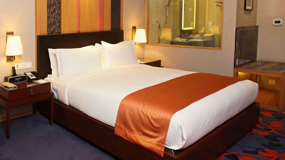 a hotel room with a large bed and a bathroom at Holiday Inn New Delhi Mayur Vihar Noida by IHG in New Delhi a hotel room with a large bed and a bathroom at Holiday Inn New Delhi Mayur Vihar Noida by IHG in New Delhi