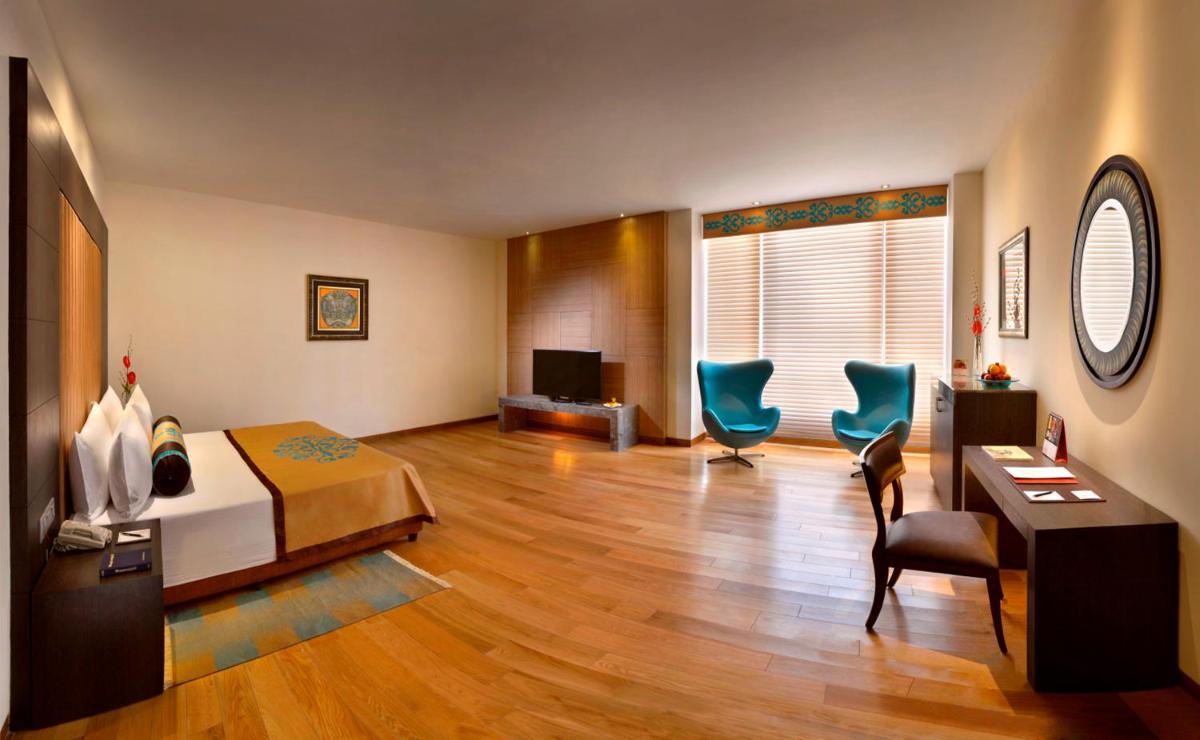 a hotel room with a bed and two blue chairs at The Lalit Great Eastern Kolkata in Kolkata a hotel room with a bed and two blue chairs at The Lalit Great Eastern Kolkata in Kolkata