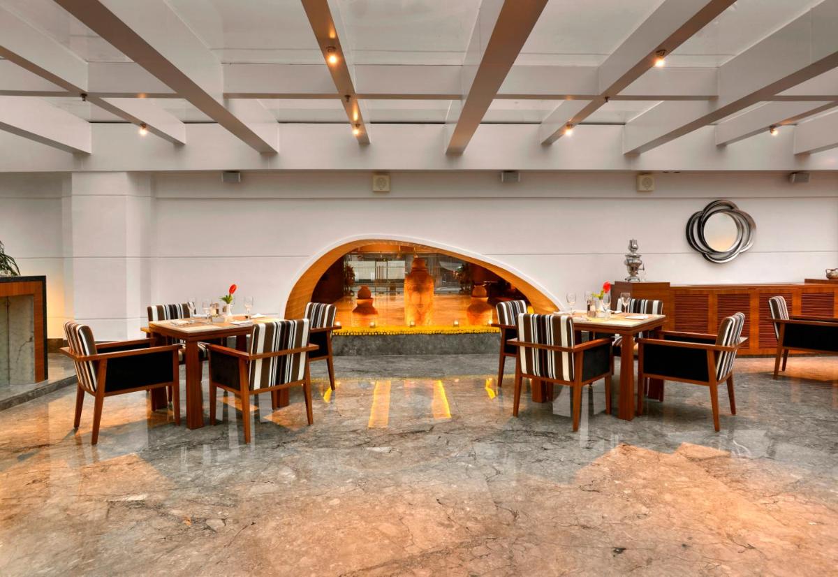 a restaurant with tables and chairs in a room at The Lalit Great Eastern Kolkata in Kolkata a restaurant with tables and chairs in a room at The Lalit Great Eastern Kolkata in Kolkata
