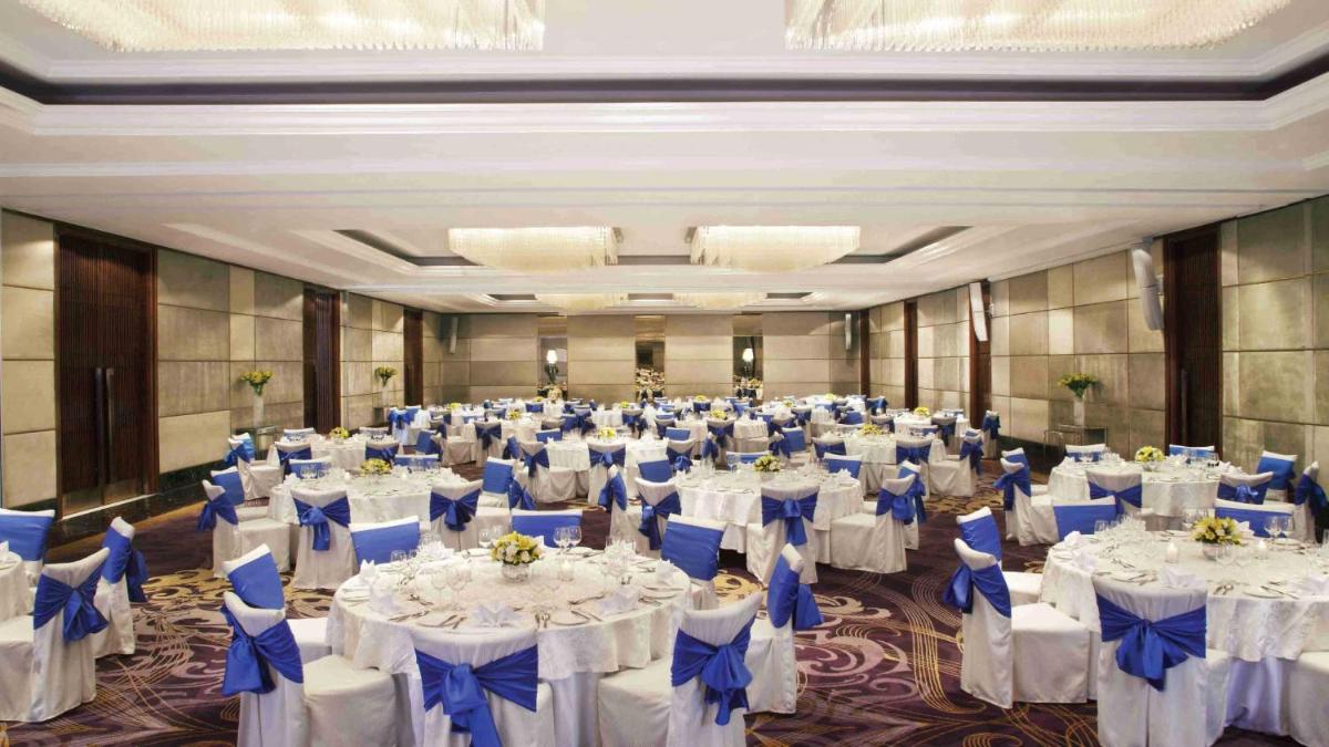 a large banquet hall with white tables and blue chairs at Holiday Inn New Delhi Mayur Vihar Noida by IHG in New Delhi a large banquet hall with white tables and blue chairs at Holiday Inn New Delhi Mayur Vihar Noida by IHG in New Delhi