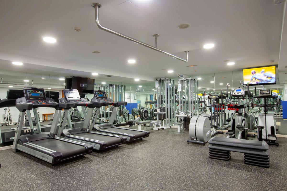 un gimnasio con filas de cintas de correr y máquinas en Hotel Carlos I Silgar, en Sanxenxo
