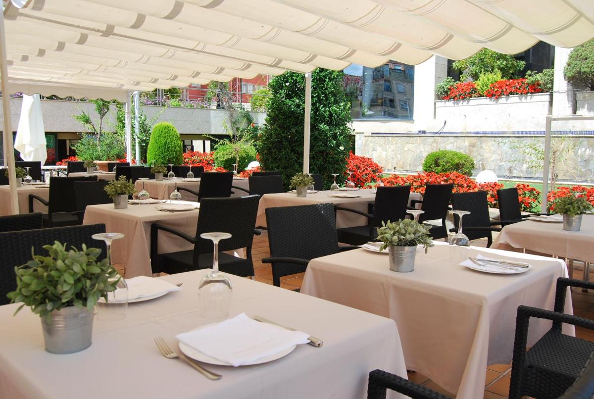 Un restaurante con mesas y sillas blancas y flores. en Hotel Carlos I Silgar, en Sanxenxo