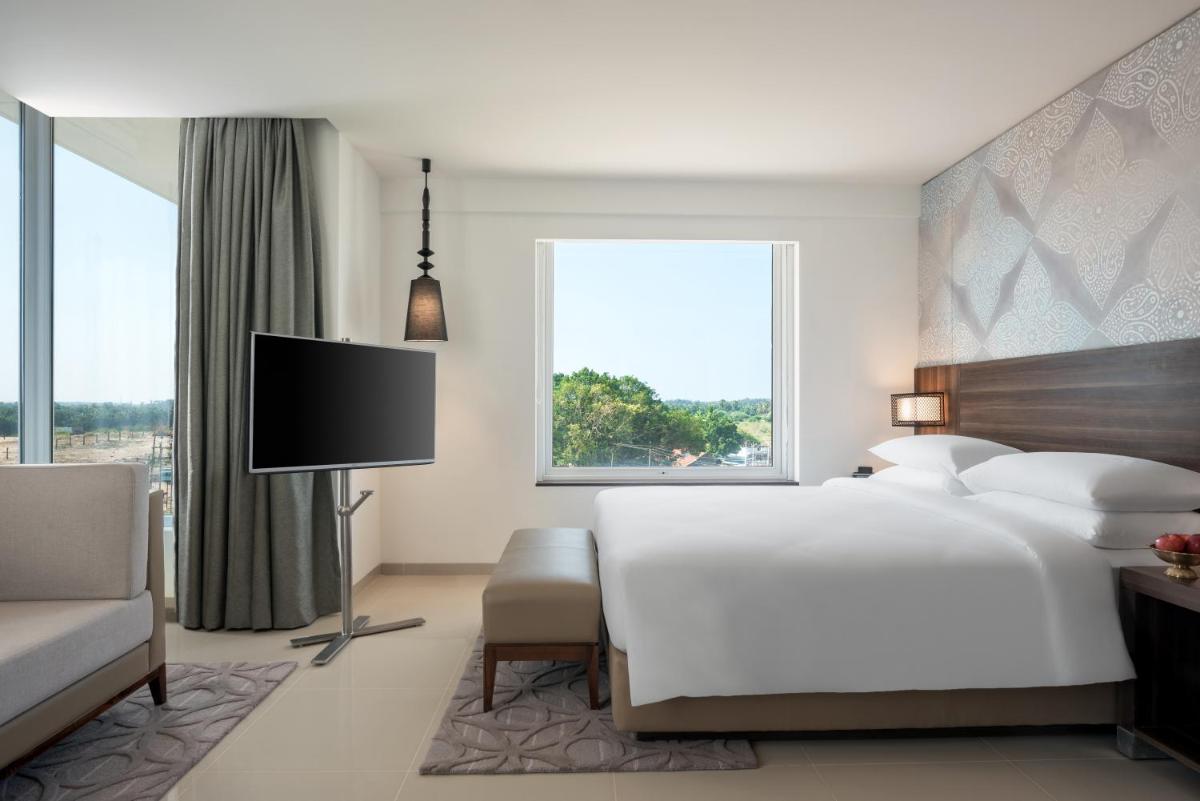a white bedroom with a large bed and a tv at The Residency Towers, Rameswaram in Rāmeswaram
